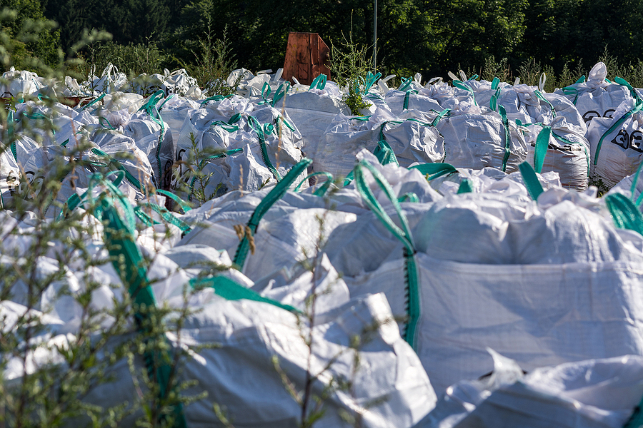 Asbestos with warning sign Lettering in German "A" for Asbestos. Asbestos stored in big bags card bags or fabric bag on the open space of a construction site.