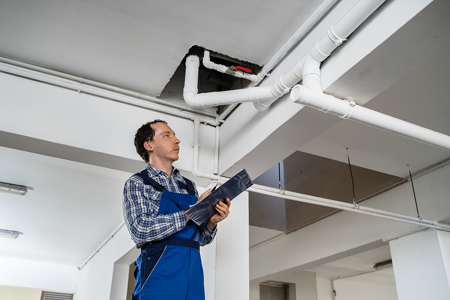 Male Worker Inspecting Pipes In Residential Building